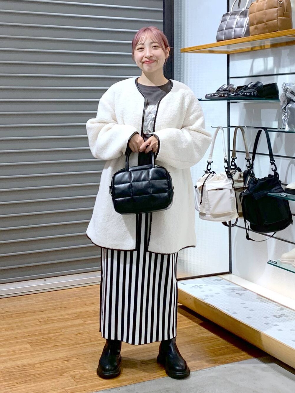 ブラック系のスカート、ホワイト系のその他アウター、ブラック系のボストンバッグを着用したレディースの秋コーディネートの3枚目の写真