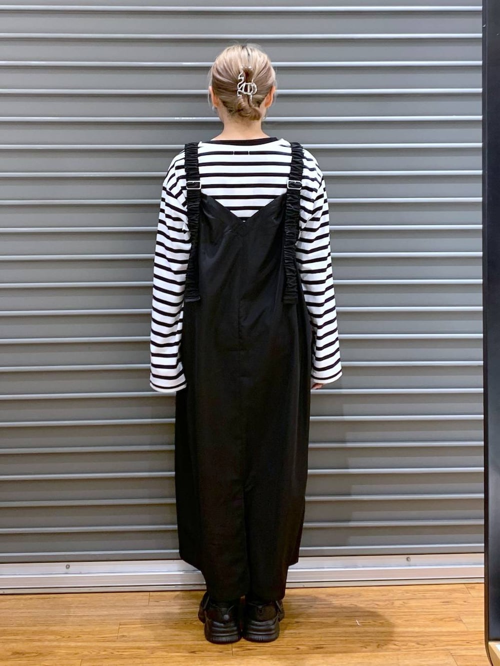 ブルー系のTシャツ/カットソー、ブラック系のスニーカー、ブラック系のジャンパースカートを着用したレディースの冬コーディネートの2枚目の写真
