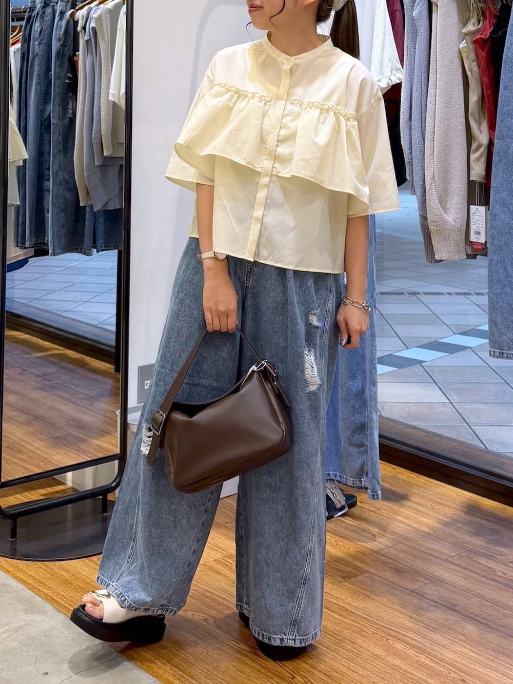 ブルー系のデニムパンツ、ホワイト系のサンダル、ブラウン系のショルダーバッグを着用したレディースの夏コーディネートの6枚目の写真