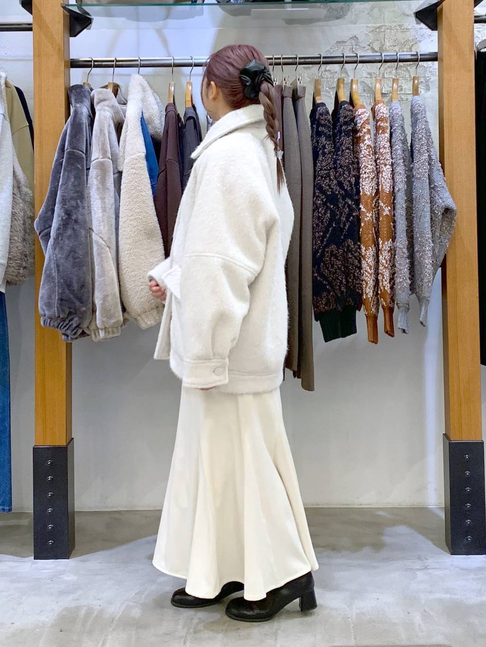 ブラック系のボストンバッグ、ブラック系のブーツ、ホワイト系のブルゾンを着用したレディースの冬コーディネートの4枚目の写真