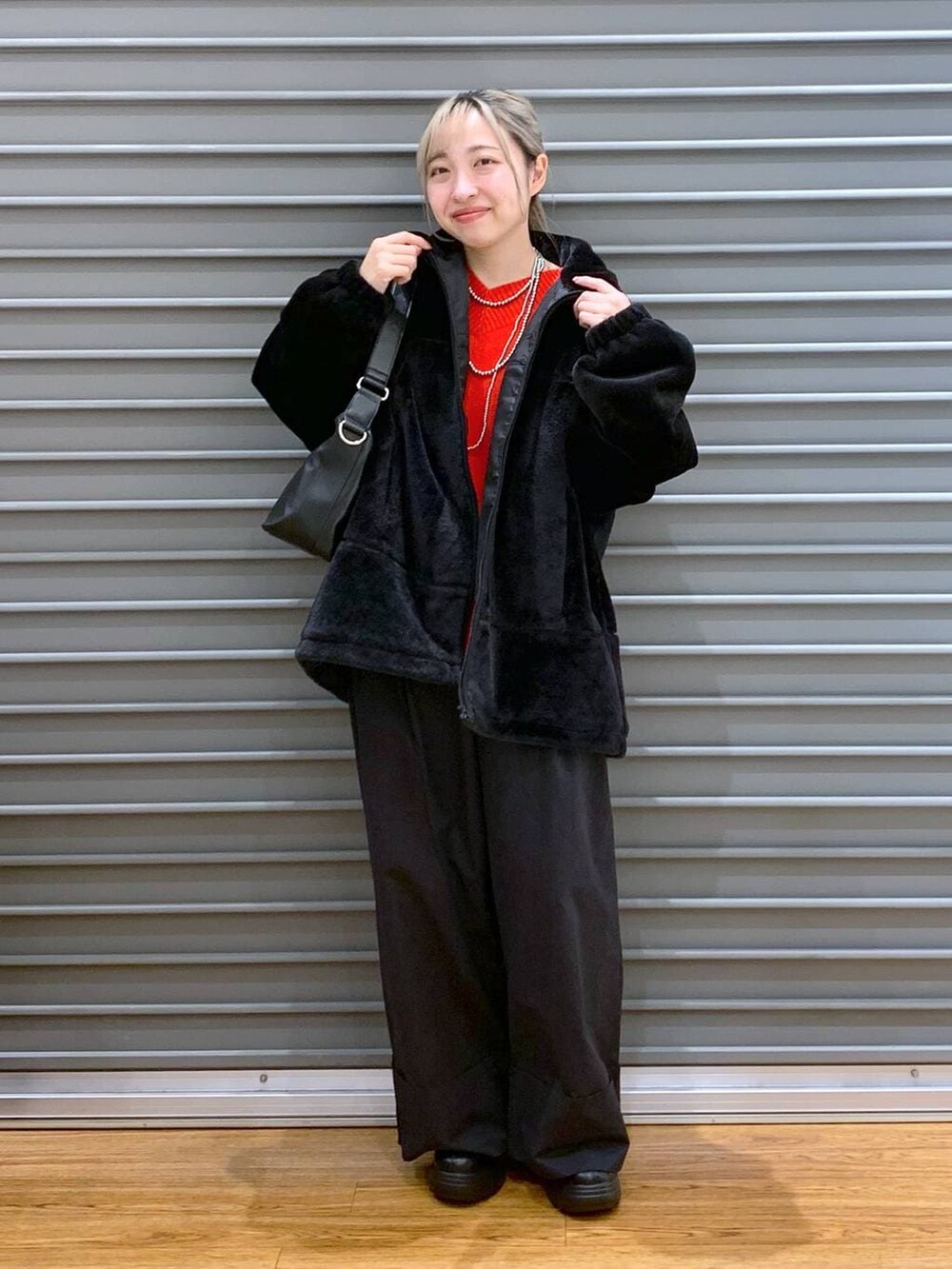 レッド系のニット/セーター、ブラック系のショルダーバッグ、ブラック系のブーツを着用したレディースの冬コーディネートの7枚目の写真