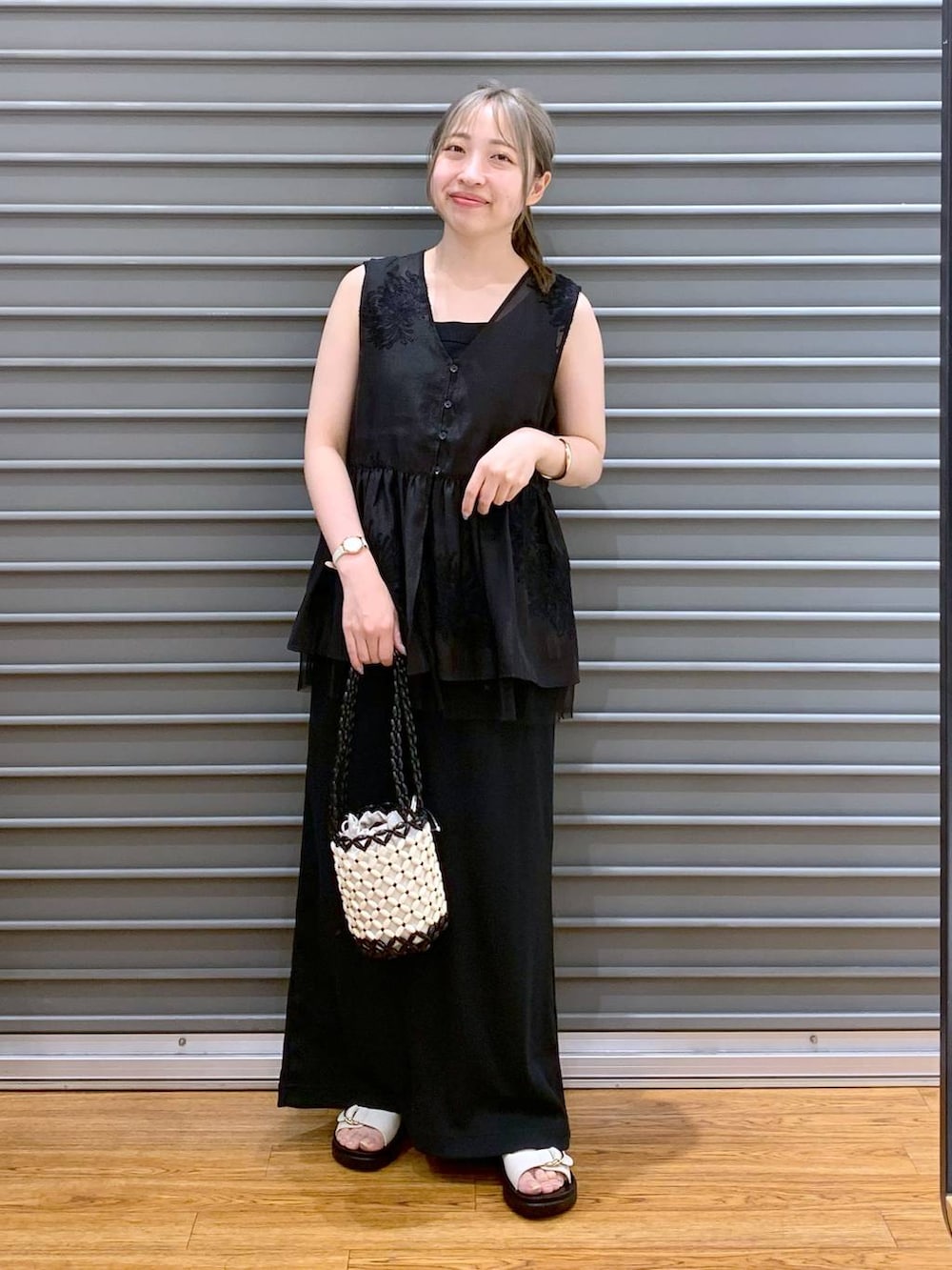 ホワイト系のサンダル、ホワイト系のハンドバッグ、ブラック系のシャツ/ブラウスを着用したレディースの夏コーディネートの6枚目の写真