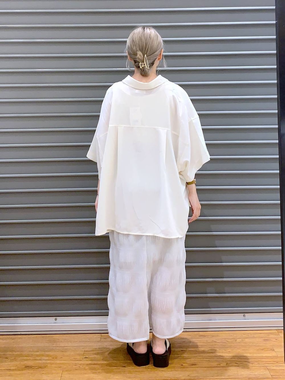 ブラック系のショルダーバッグ、ホワイト系のサンダル、ホワイト系のシャツ/ブラウスを着用したレディースの夏コーディネートの2枚目の写真