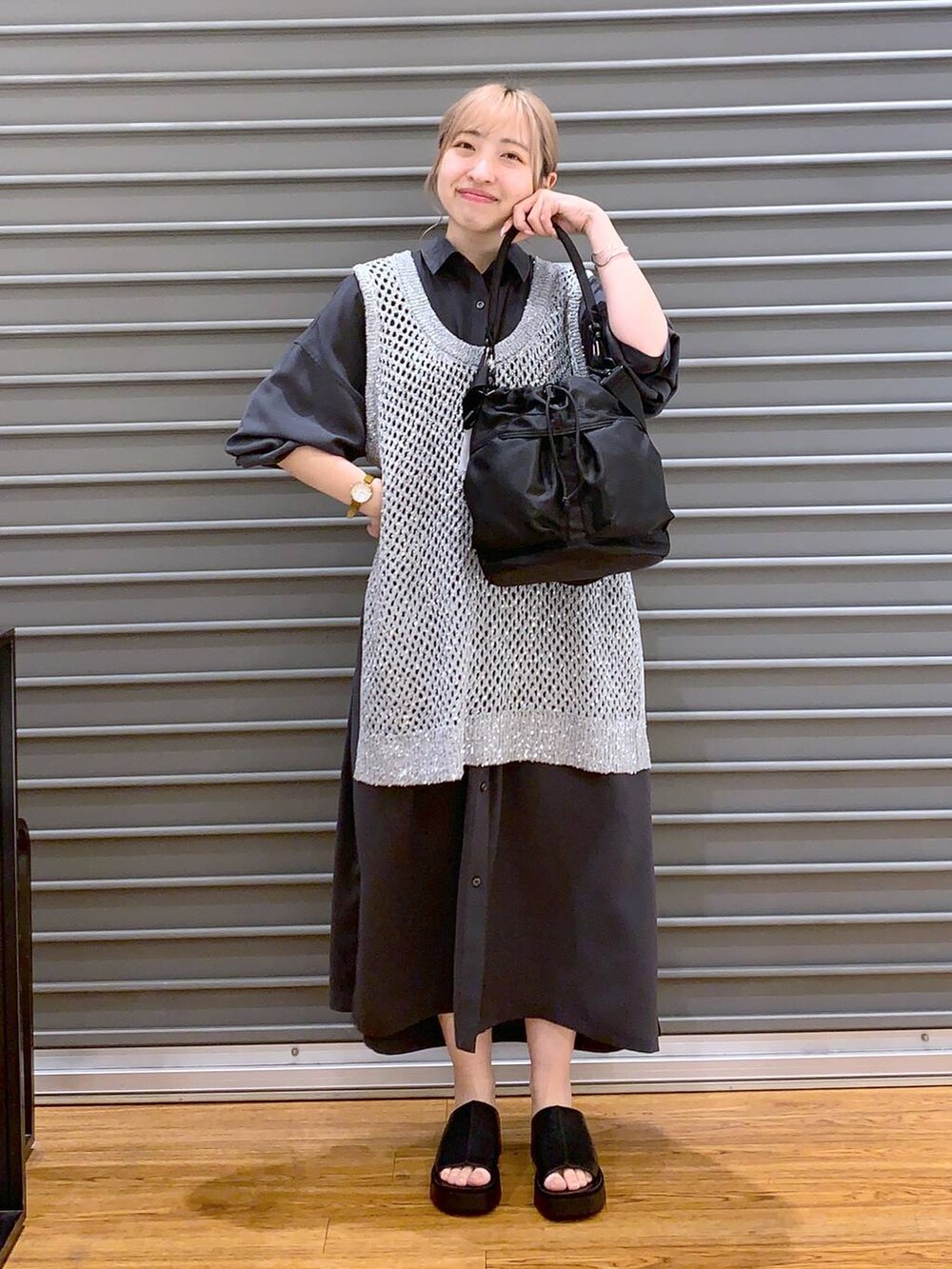 グレー系のベスト、グレー系のワンピース、ブラック系のショルダーバッグを着用したレディースの春コーディネートの3枚目の写真
