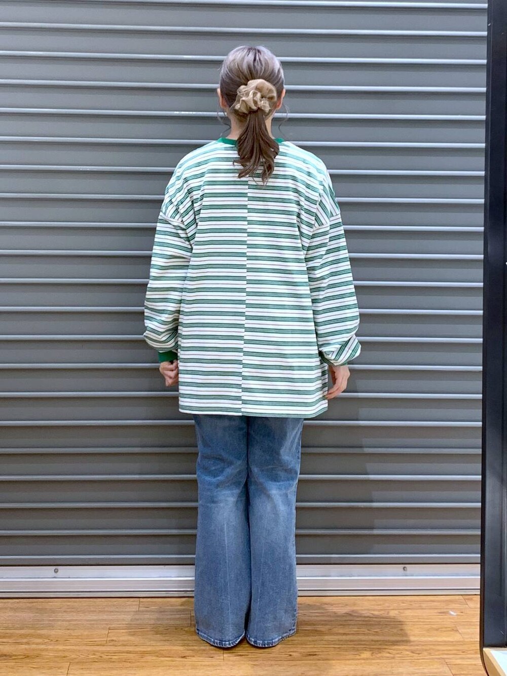 グリーン系のワンピース、ブルー系のデニムパンツ、ブラック系のパンプスを着用したレディースの春コーディネートの3枚目の写真