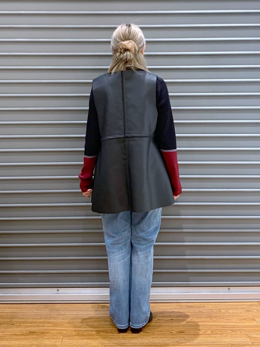 ブルー系のデニムパンツ、ブラック系のニット/セーター、ブラック系のショルダーバッグを着用したレディースの秋コーディネートの2枚目の写真