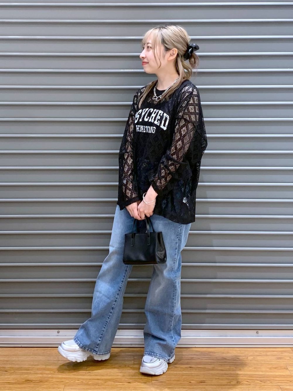 ブルー系のデニムパンツ、ブラック系のタンクトップ、シルバー系のスニーカーを着用したレディースの春コーディネートの4枚目の写真