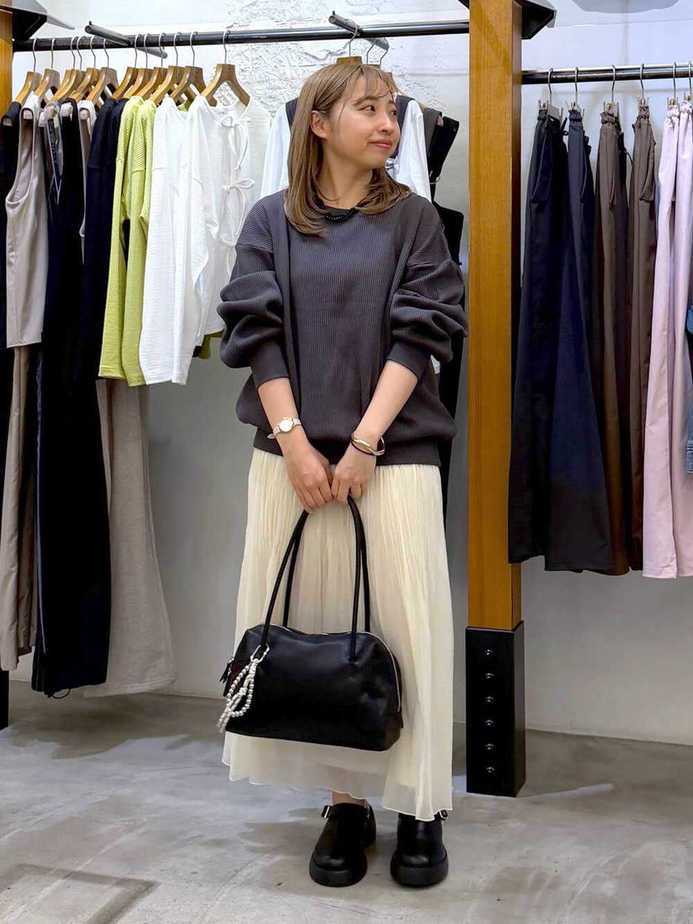 ブラック系のサンダル、ブラック系のボストンバッグ、ホワイト系のスカートを着用したレディースの春コーディネートの6枚目の写真