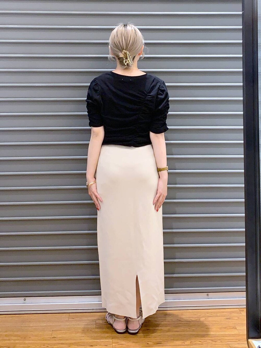 ブラック系のショルダーバッグ、ベージュ系のスカート、シルバー系のサンダルを着用したレディースの春コーディネートの2枚目の写真