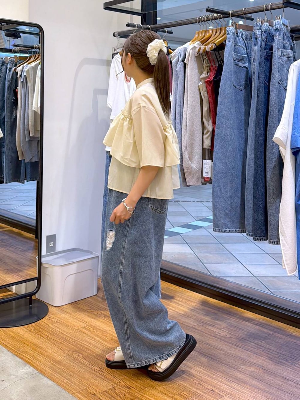 ブルー系のデニムパンツ、ホワイト系のサンダル、ブラウン系のショルダーバッグを着用したレディースの夏コーディネートの3枚目の写真