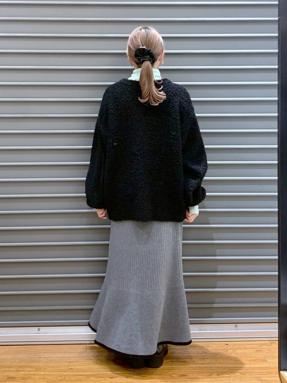 ブラック系のブーツ、ブラック系のワンピース、グリーン系のTシャツ/カットソーを着用したレディースの冬コーディネートの2枚目の写真