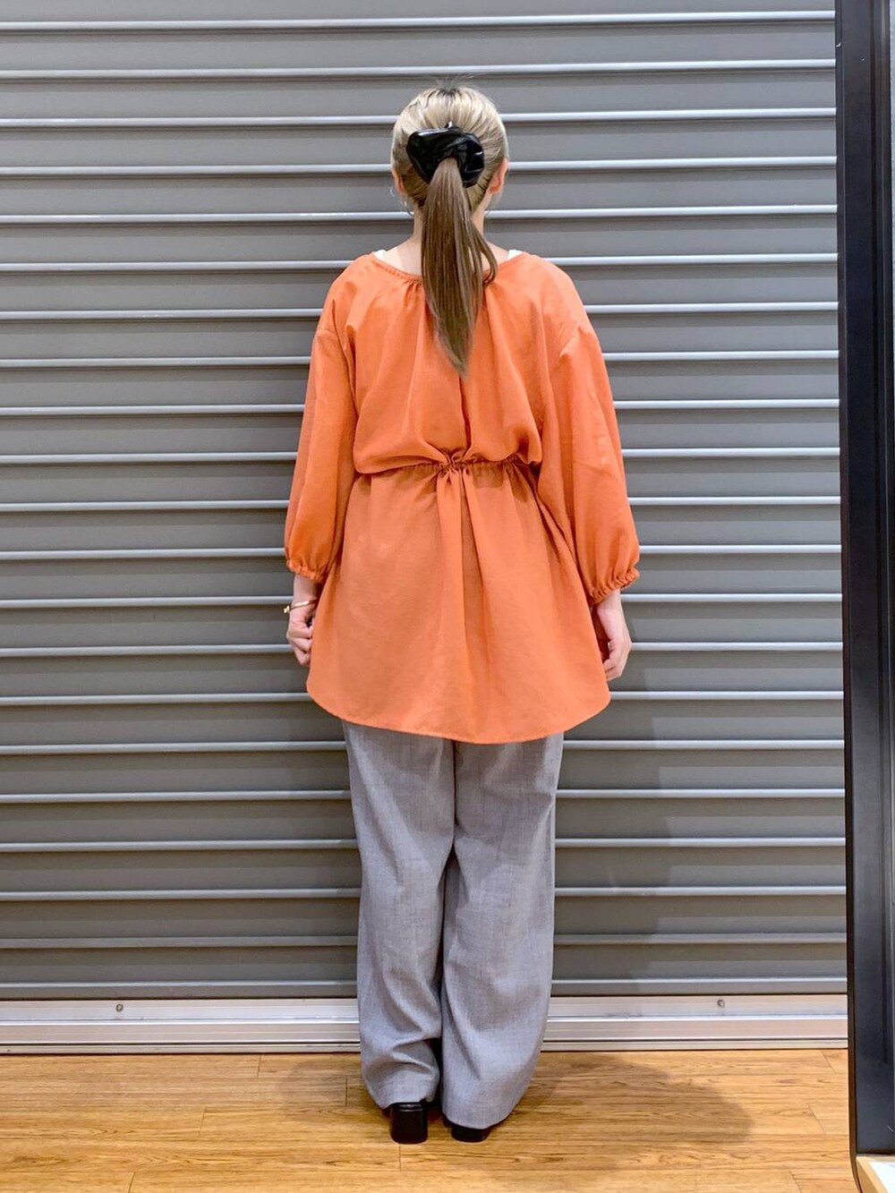 オレンジ系のシャツ/ブラウス、グレー系のショルダーバッグ、ブラック系のサンダルを着用したレディースの夏コーディネートの2枚目の写真