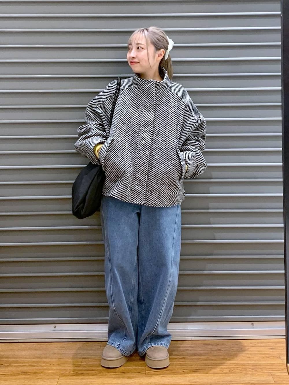 イエロー系のニット/セーター、ブラック系のブルゾン、ブラック系のトートバッグを着用したレディースの冬コーディネートの7枚目の写真