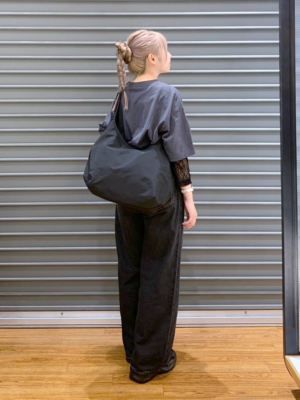 ブラック系のデニムパンツ、ブラック系のスニーカー、ブラック系のショルダーバッグを着用したレディースの秋コーディネートの4枚目の写真