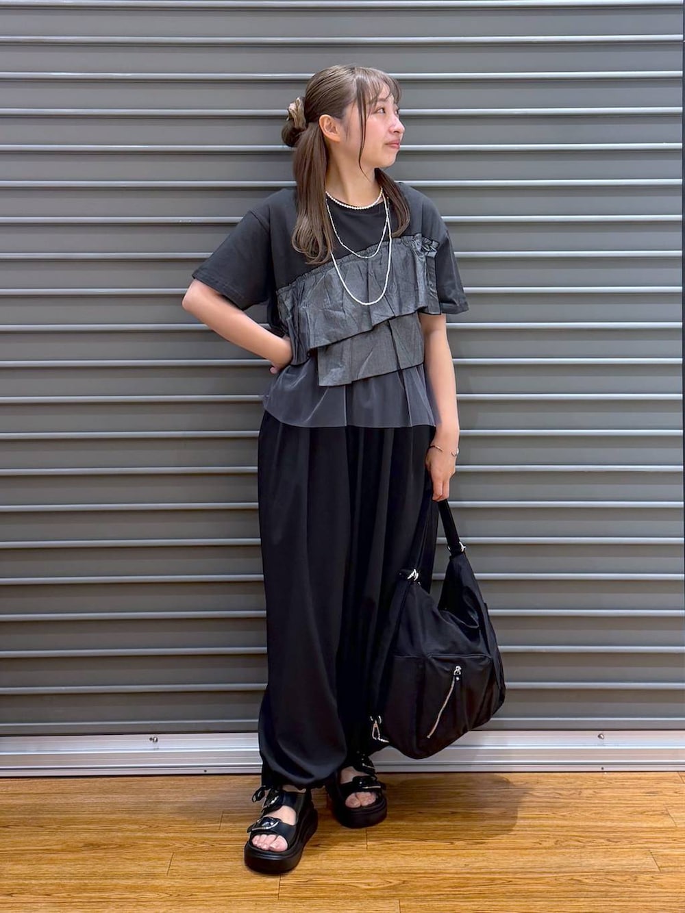 ブラック系のショルダーバッグ、ブラック系のサンダル、グレー系のTシャツ/カットソーを着用したレディースの夏コーディネートの4枚目の写真
