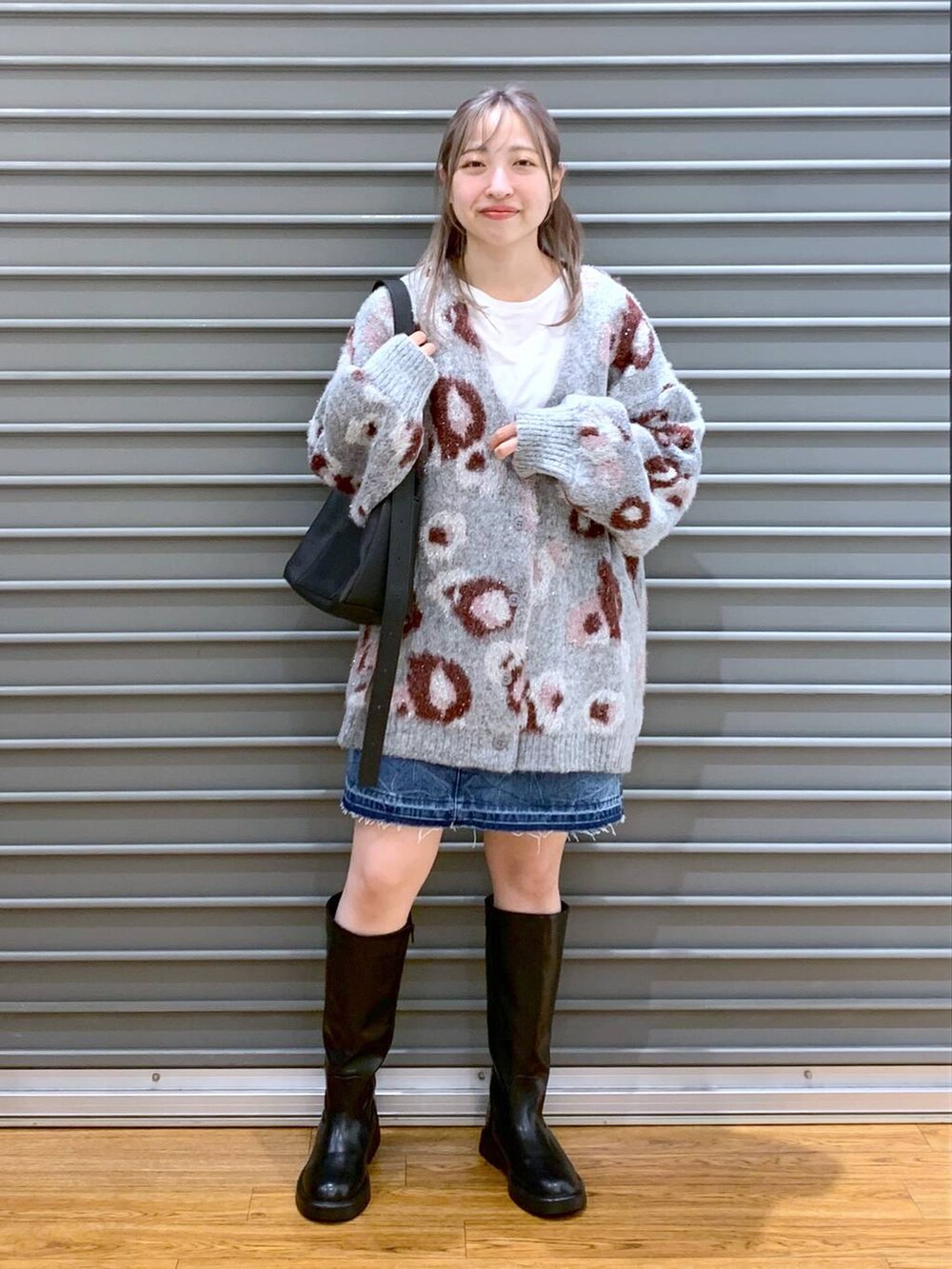 ブルー系のデニムスカート、ブラック系のショルダーバッグ、ブラック系のブーツを着用したレディースの冬コーディネートの5枚目の写真