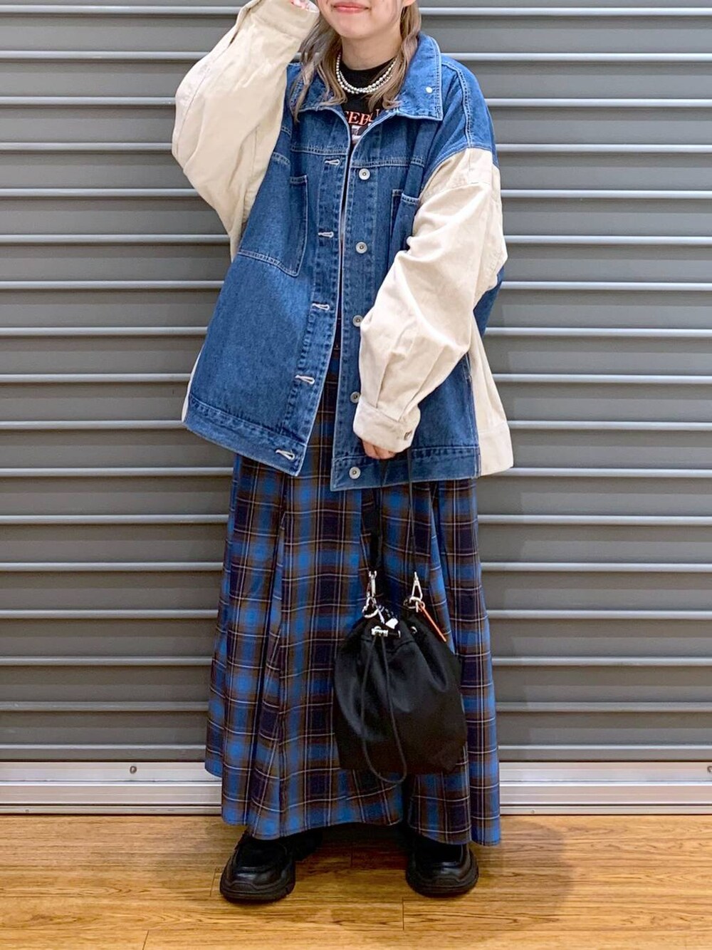 ブラック系のショルダーバッグ、ブラック系のスニーカー、ブルー系のカバーオールを着用したレディースの秋コーディネートの6枚目の写真