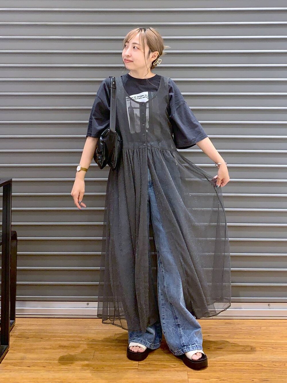 ブラック系のショルダーバッグ、ブルー系のデニムパンツ、ホワイト系のサンダルを着用したレディースの秋コーディネートの3枚目の写真