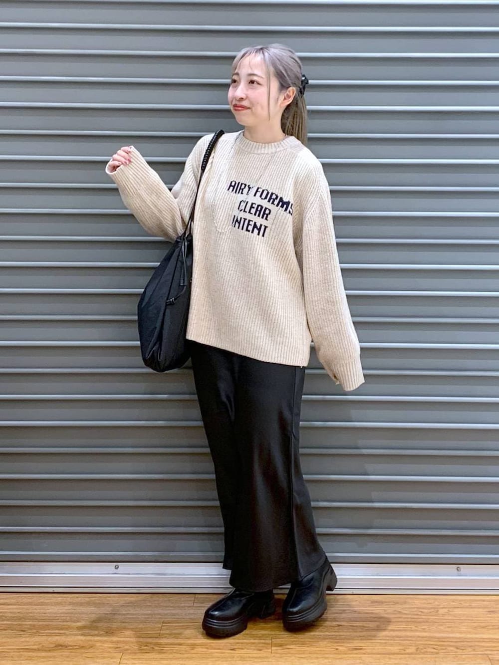 ブラック系のスカート、ブラック系のブーツ、ブラック系のトートバッグを着用したレディースの冬コーディネートの4枚目の写真