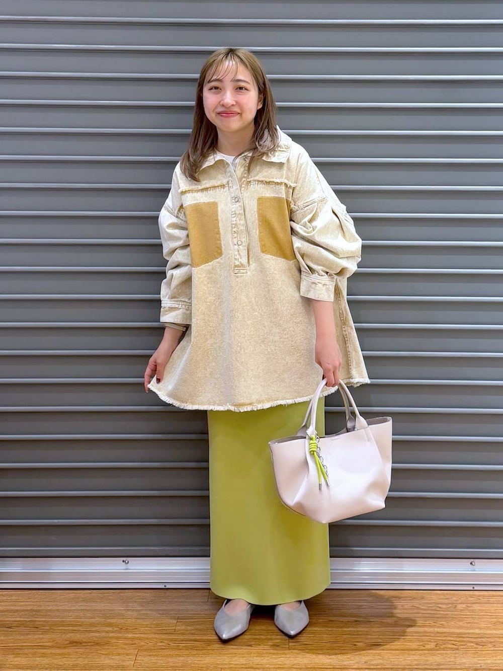 グリーン系のスカート、シルバー系のパンプス、ホワイト系のトートバッグを着用したレディースの春コーディネートの6枚目の写真