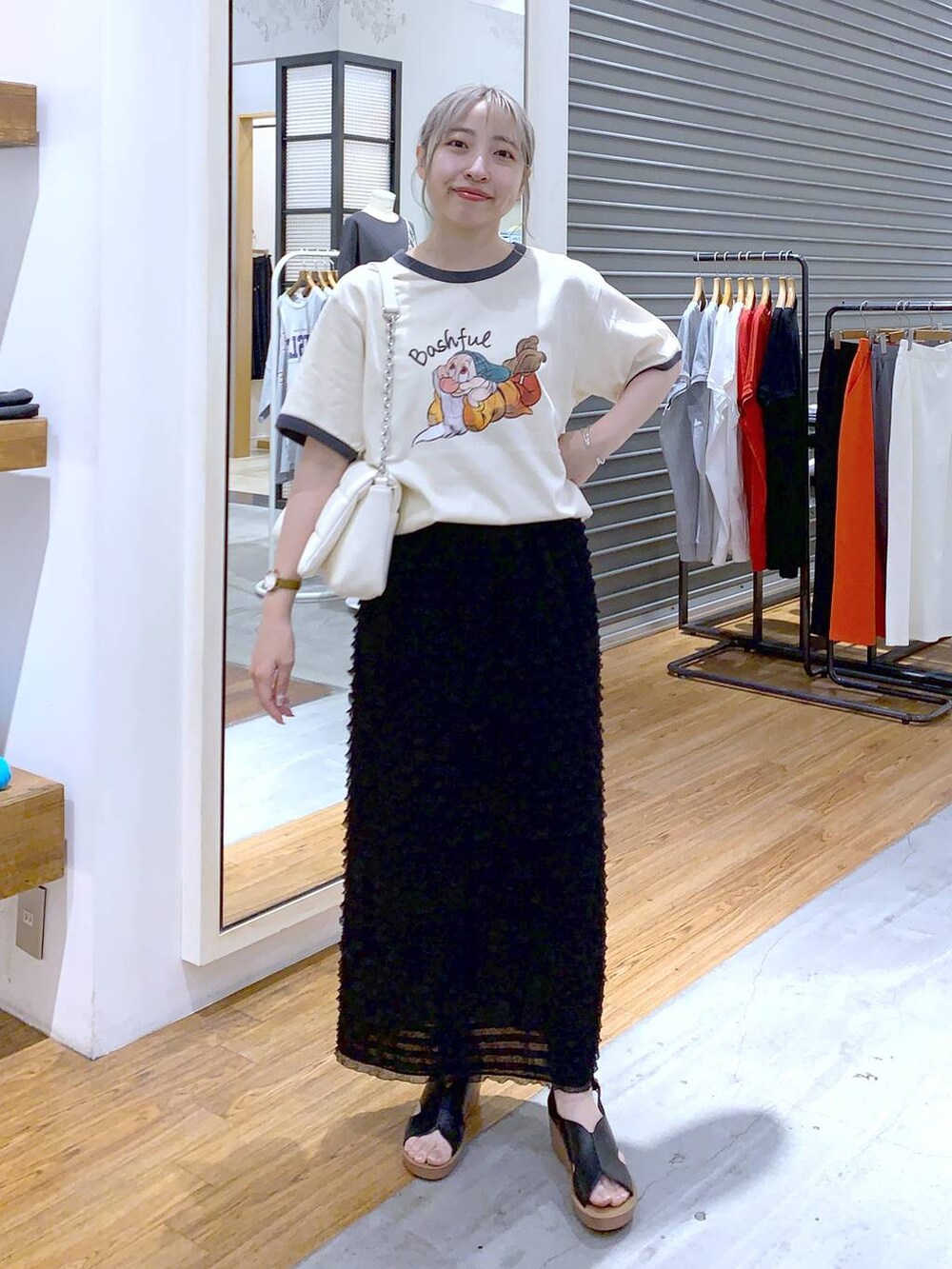 ホワイト系のショルダーバッグ、ブラック系のスカート、ブラック系のサンダルを着用したレディースの夏コーディネートの3枚目の写真