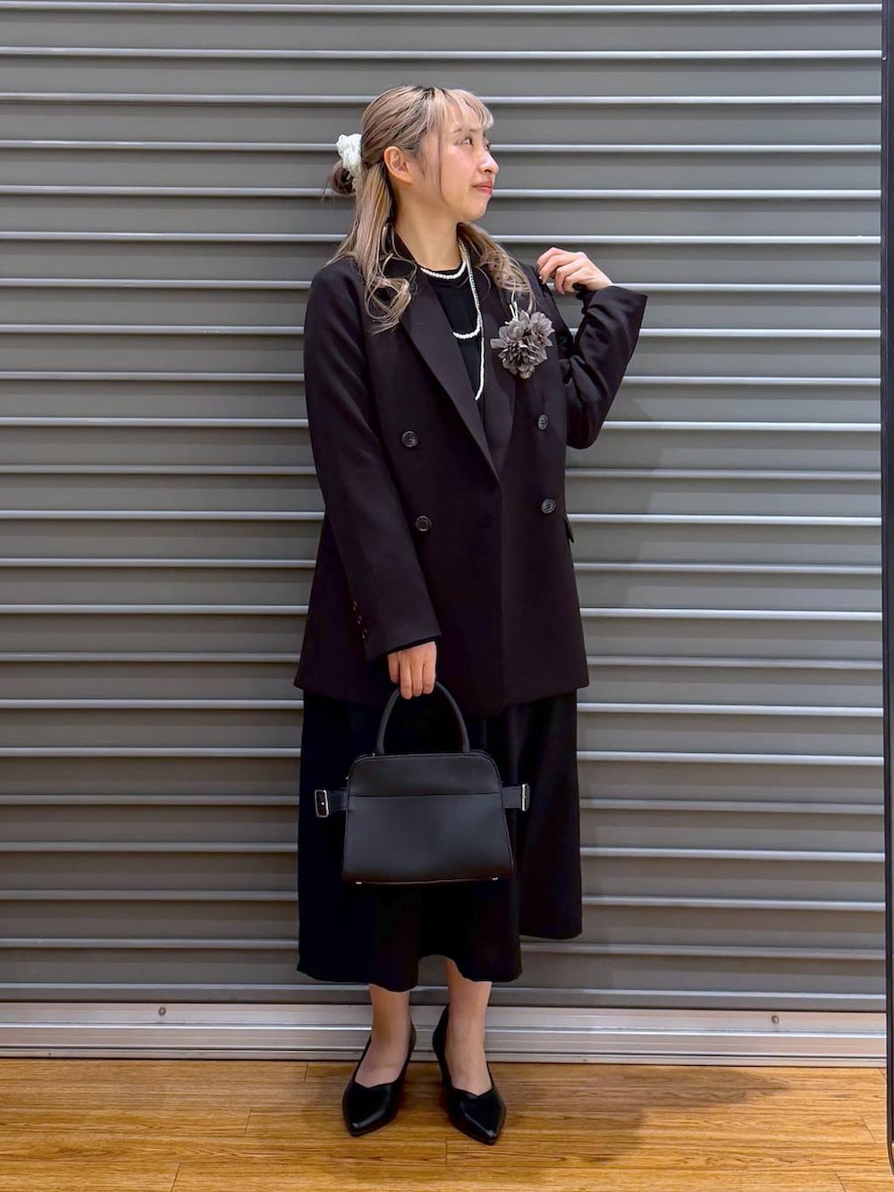 ブラック系のテーラードジャケット、ブラック系のワンピース、ブラック系のショルダーバッグを着用したレディースの冬コーディネートの8枚目の写真