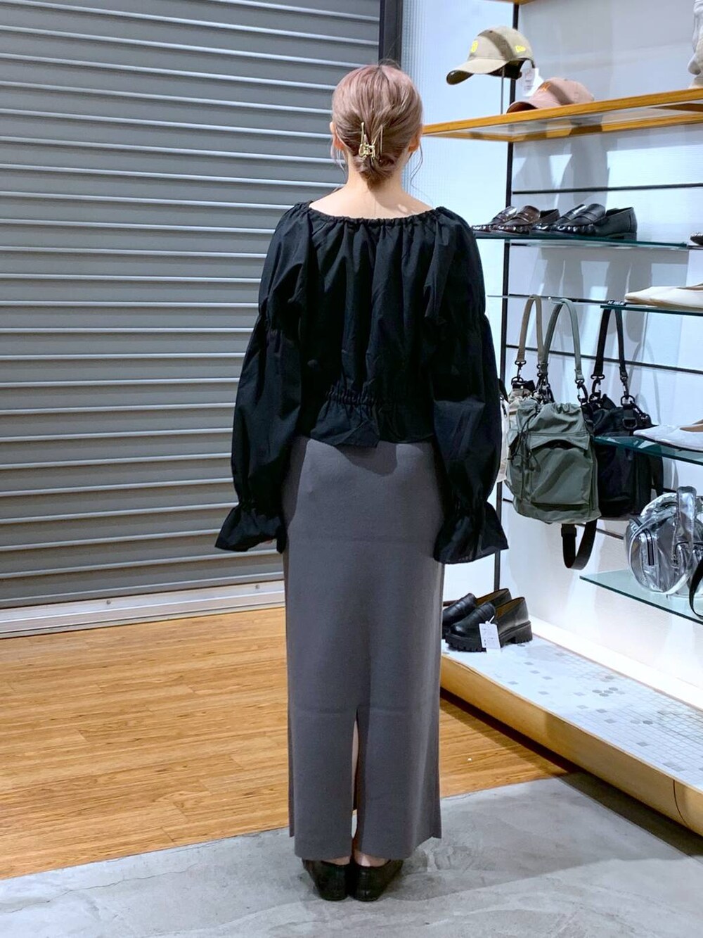 ホワイト系のショルダーバッグ、ブラック系のパンプス、グレー系のスカートを着用したレディースの秋コーディネートの2枚目の写真