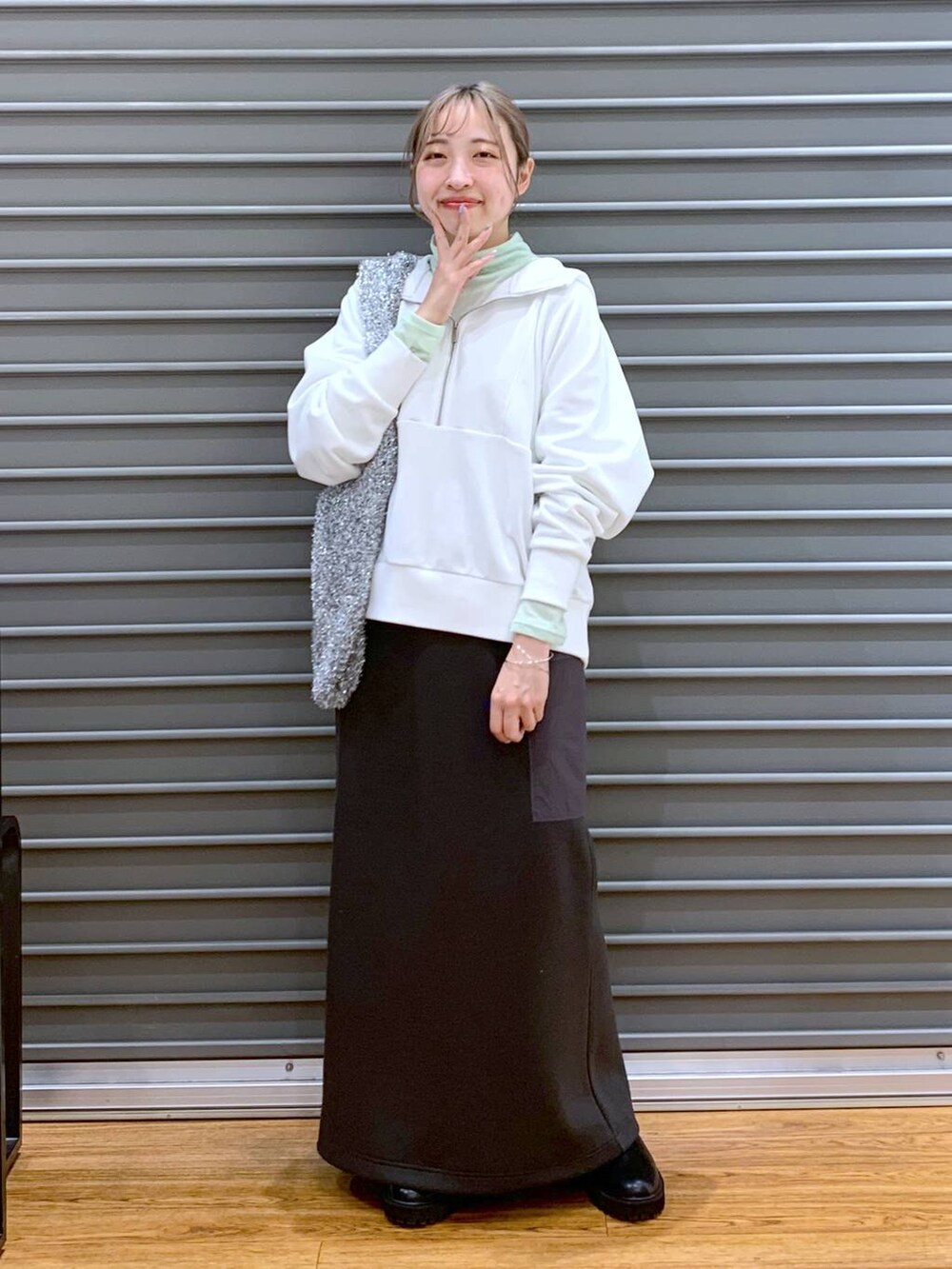 ブラック系のブーツ、シルバー系のショルダーバッグ、グレー系のスカートを着用したレディースの冬コーディネートの6枚目の写真