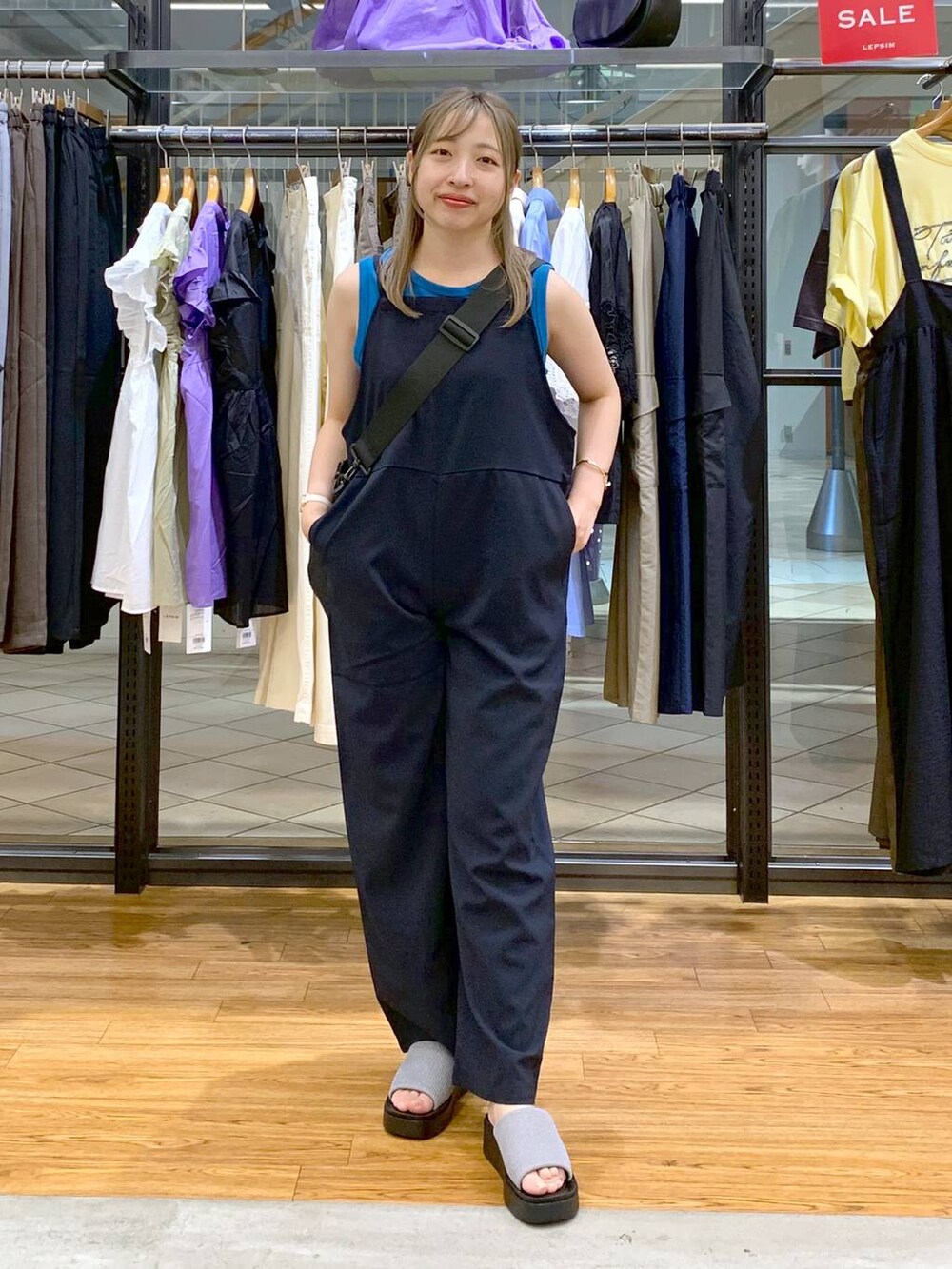 ブルー系のタンクトップ、シルバー系のサンダル、ブラック系のショルダーバッグを着用したレディースの秋コーディネートの4枚目の写真