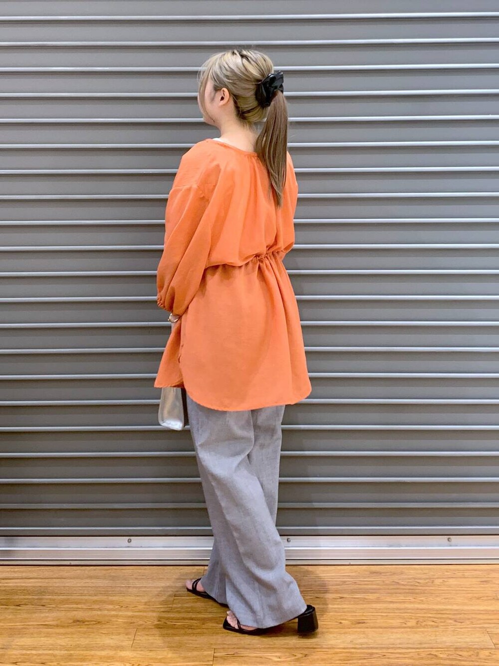 オレンジ系のシャツ/ブラウス、グレー系のショルダーバッグ、ブラック系のサンダルを着用したレディースの夏コーディネートの3枚目の写真