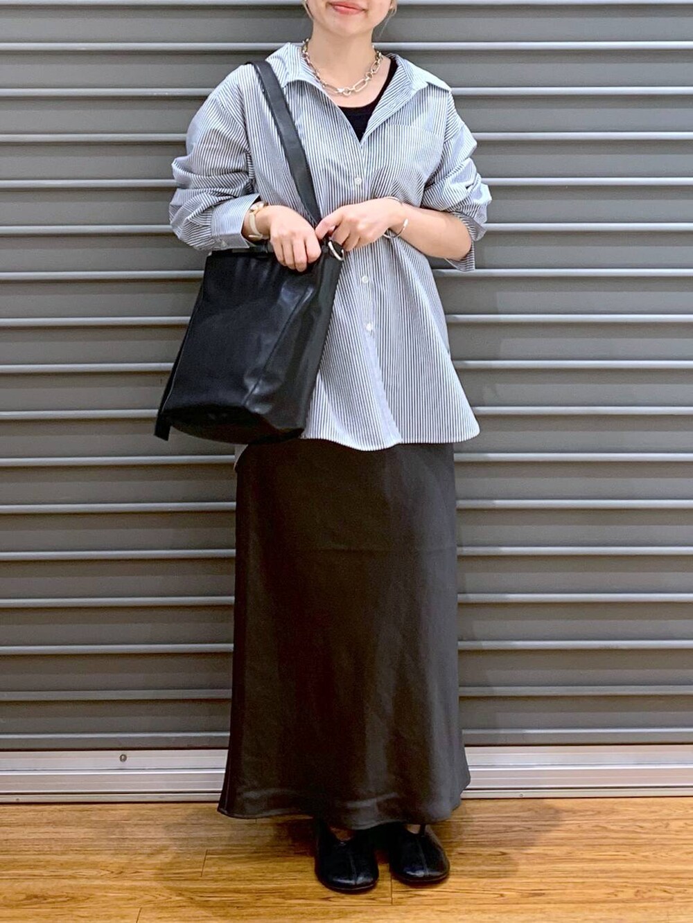 グレー系のスカート、ブラック系のショルダーバッグ、ブラック系のパンプスを着用したレディースの秋コーディネートの6枚目の写真