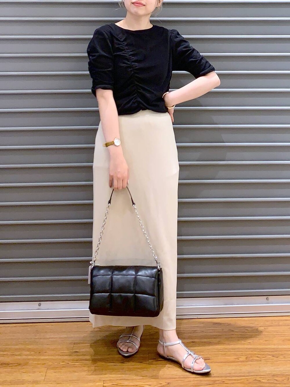 ブラック系のショルダーバッグ、ベージュ系のスカート、シルバー系のサンダルを着用したレディースの春コーディネートの4枚目の写真