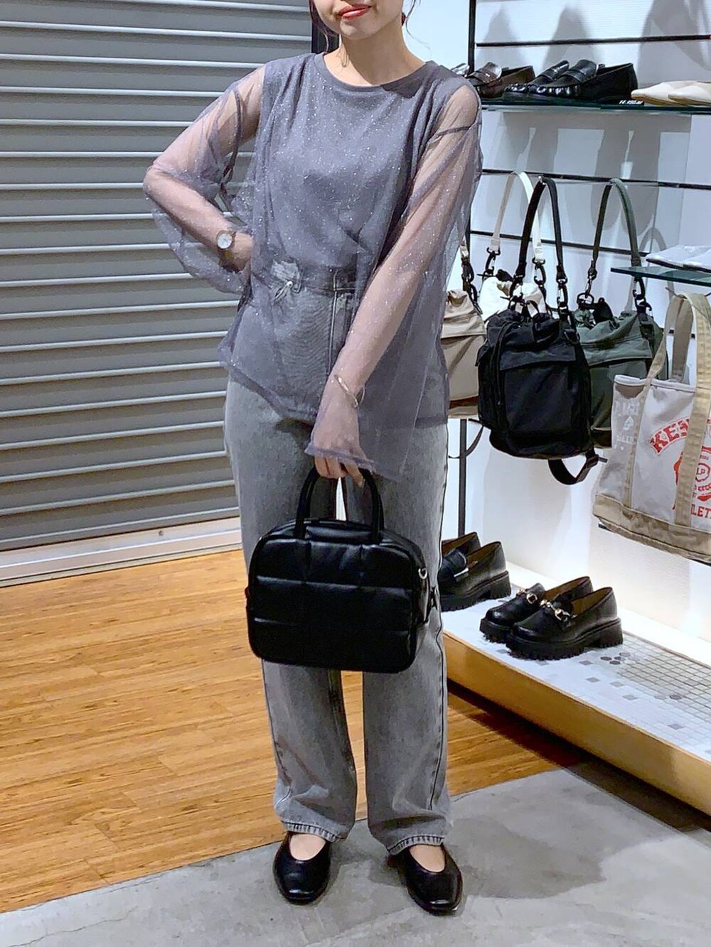 グレー系のデニムパンツ、ブラック系のパンプス、ブラック系のボストンバッグを着用したレディースの秋コーディネートの3枚目の写真