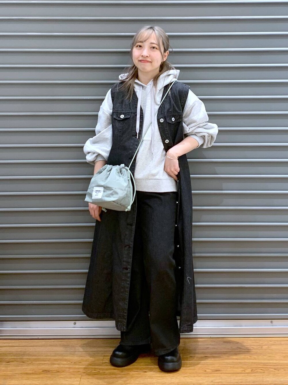 グレー系のパーカー、ブラック系のデニムパンツ、グリーン系のショルダーバッグを着用したレディースの春コーディネートの3枚目の写真