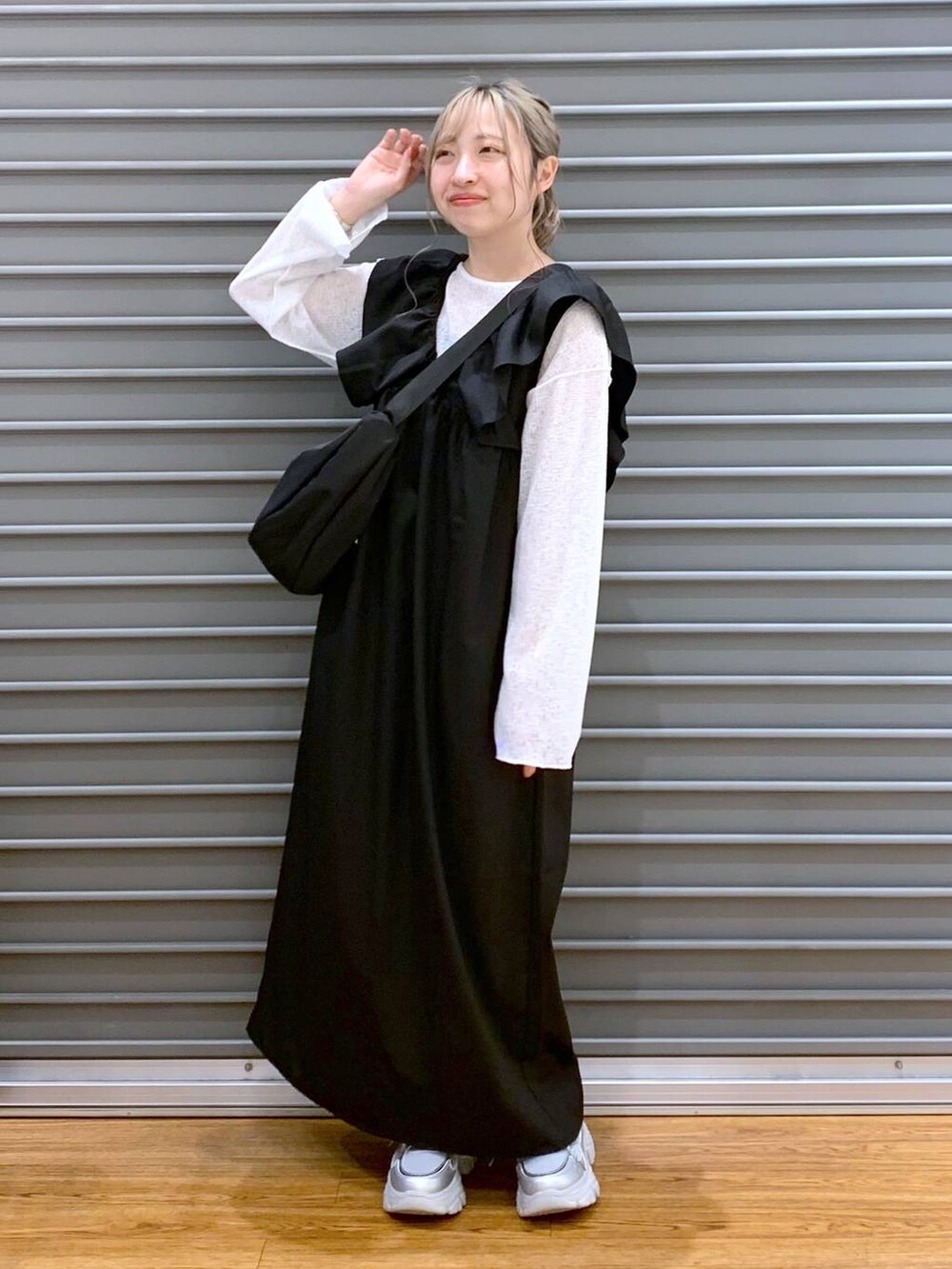 ブラック系のジャンパースカート、シルバー系のスニーカー、ホワイト系のTシャツ/カットソーを着用したレディースの春コーディネートの6枚目の写真