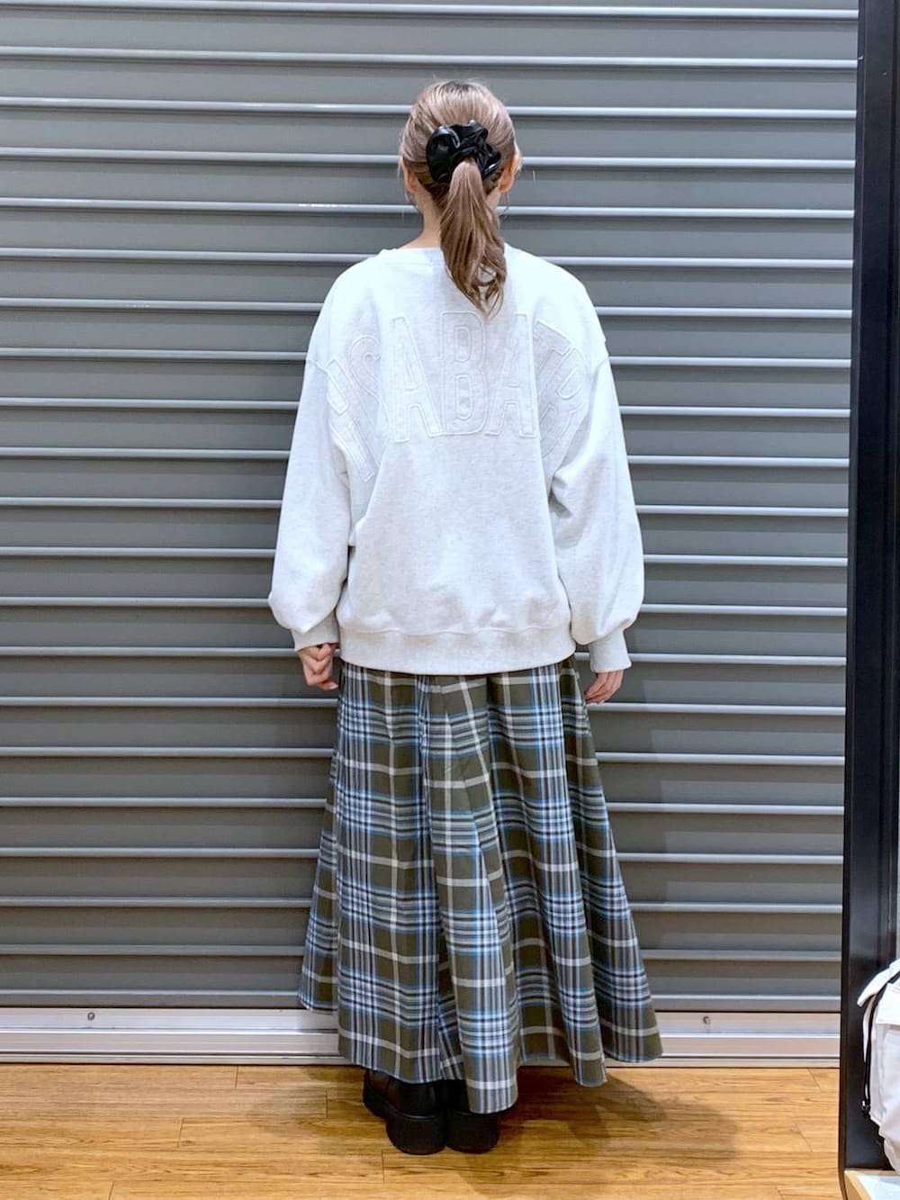 シルバー系のトートバッグ、ブラック系のブーツ、グリーン系のスカートを着用したレディースの冬コーディネートの2枚目の写真