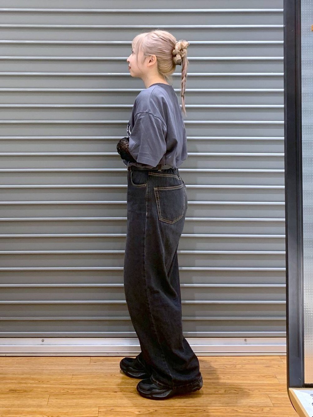 ブラック系のデニムパンツ、ブラック系のスニーカー、ブラック系のショルダーバッグを着用したレディースの秋コーディネートの3枚目の写真