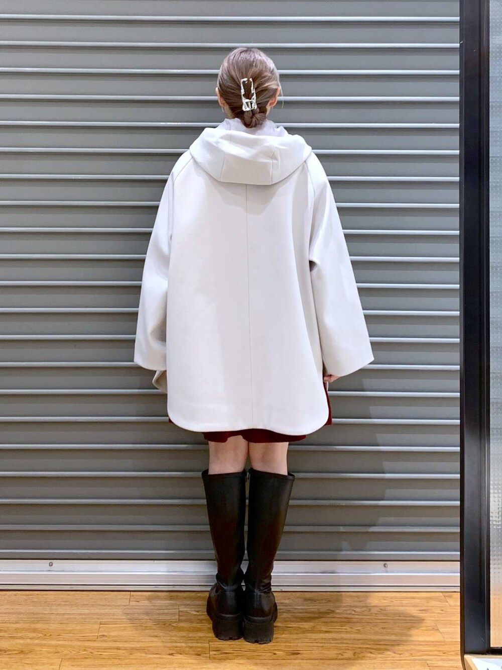 ホワイト系のポンチョ、ホワイト系のニット/セーター、ブラック系のブーツを着用したレディースの冬コーディネートの2枚目の写真