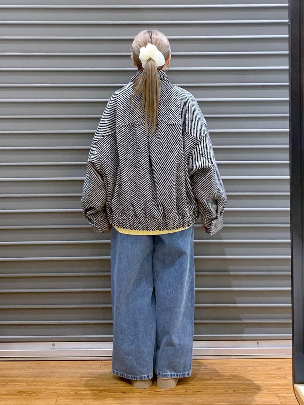 イエロー系のニット/セーター、ブラック系のブルゾン、ブラック系のトートバッグを着用したレディースの冬コーディネートの2枚目の写真