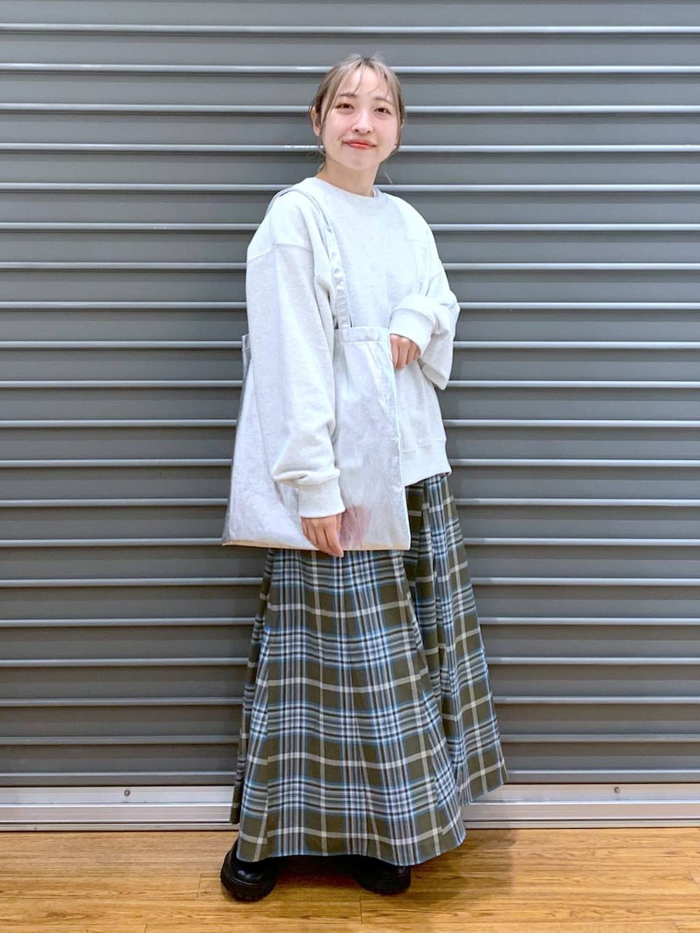 シルバー系のトートバッグ、ブラック系のブーツ、グリーン系のスカートを着用したレディースの冬コーディネートの9枚目の写真