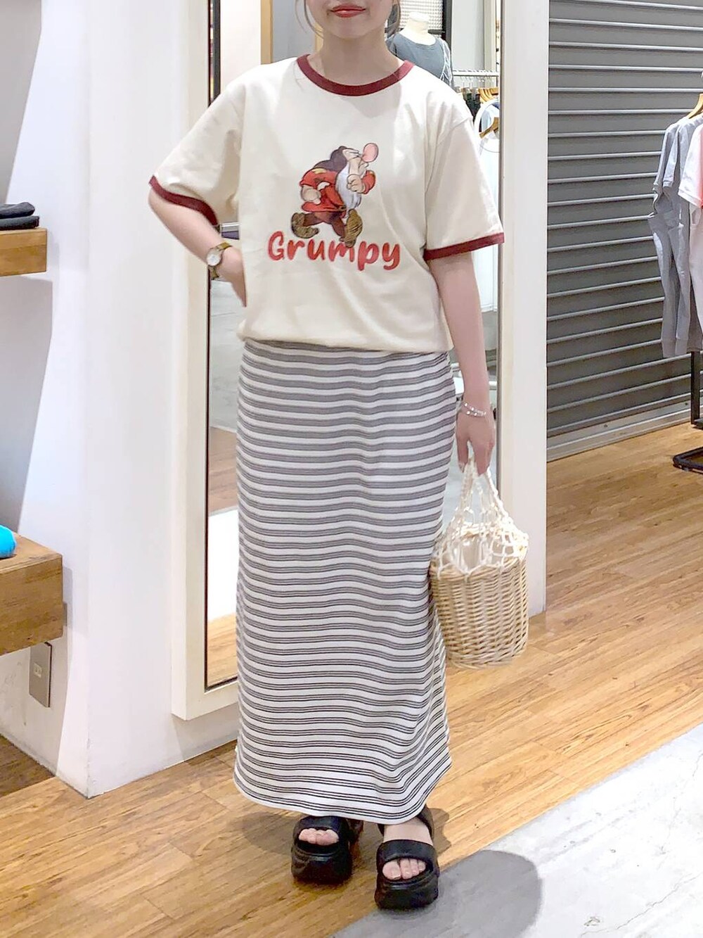 ブラック系のサンダル、ホワイト系のかごバッグ、ホワイト系のスカートを着用したレディースの夏コーディネートの2枚目の写真