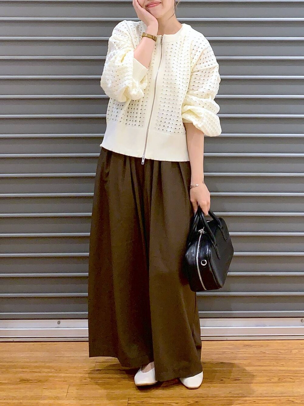 ブラウン系のスラックス、ホワイト系のパンプス、ブラック系のボストンバッグを着用したレディースの秋コーディネートの4枚目の写真