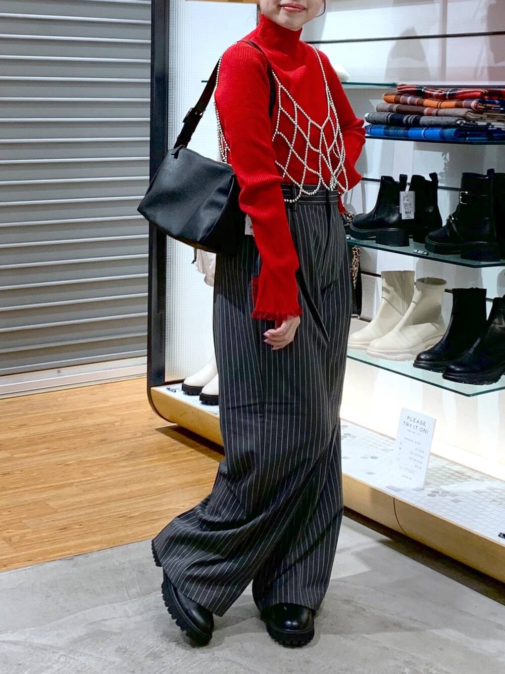 ホワイト系のベスト、ブラック系のブーツ、ブラック系のショルダーバッグを着用したレディースの冬コーディネートの6枚目の写真