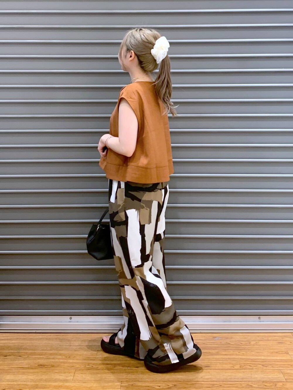 ブラック系のサンダル、オレンジ系のシャツ/ブラウス、ブラック系のショルダーバッグを着用したレディースの夏コーディネートの3枚目の写真