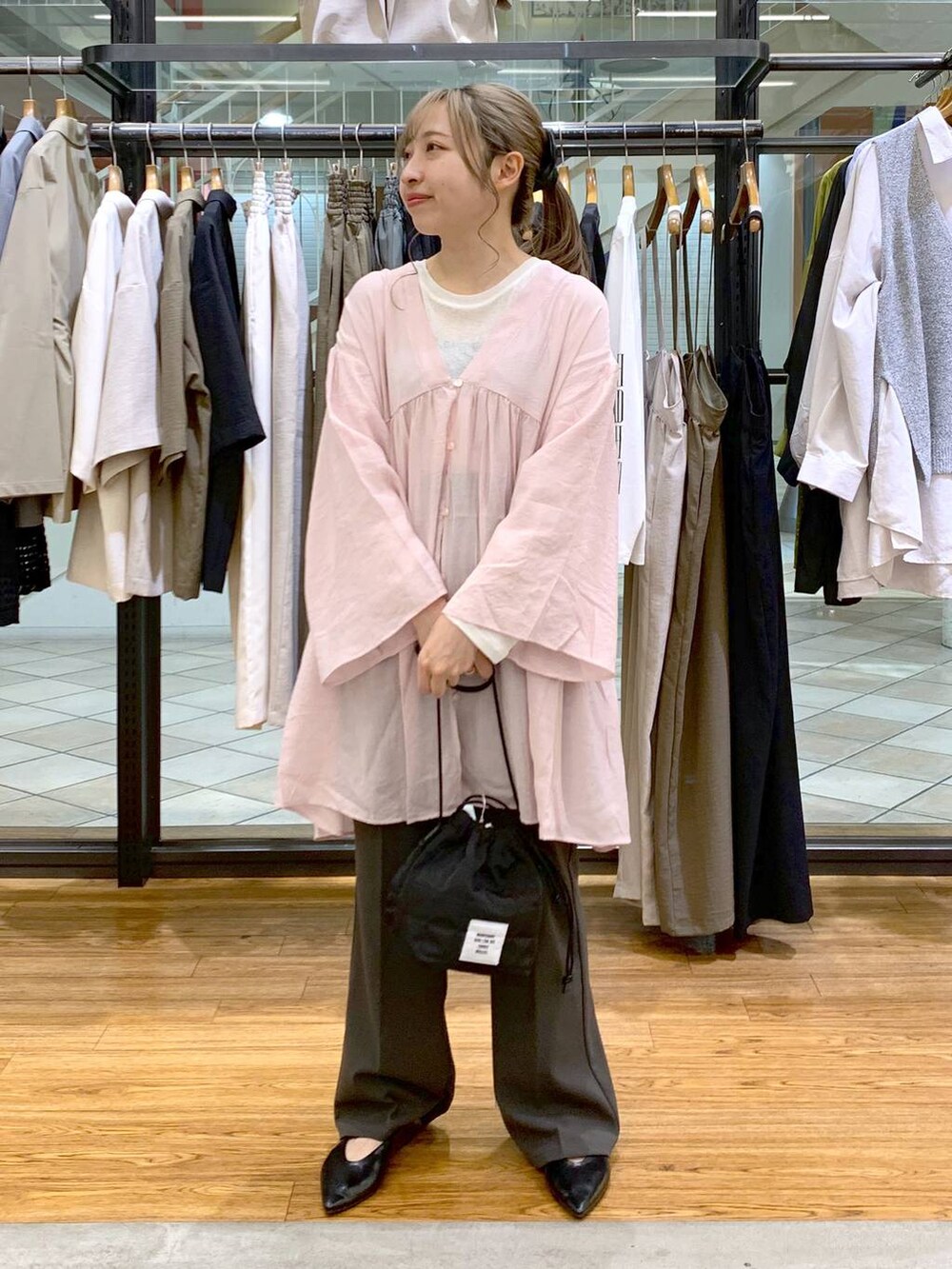 ホワイト系のTシャツ/カットソー、グレー系のスラックス、ブラック系のショルダーバッグを着用したレディースの春コーディネートの3枚目の写真