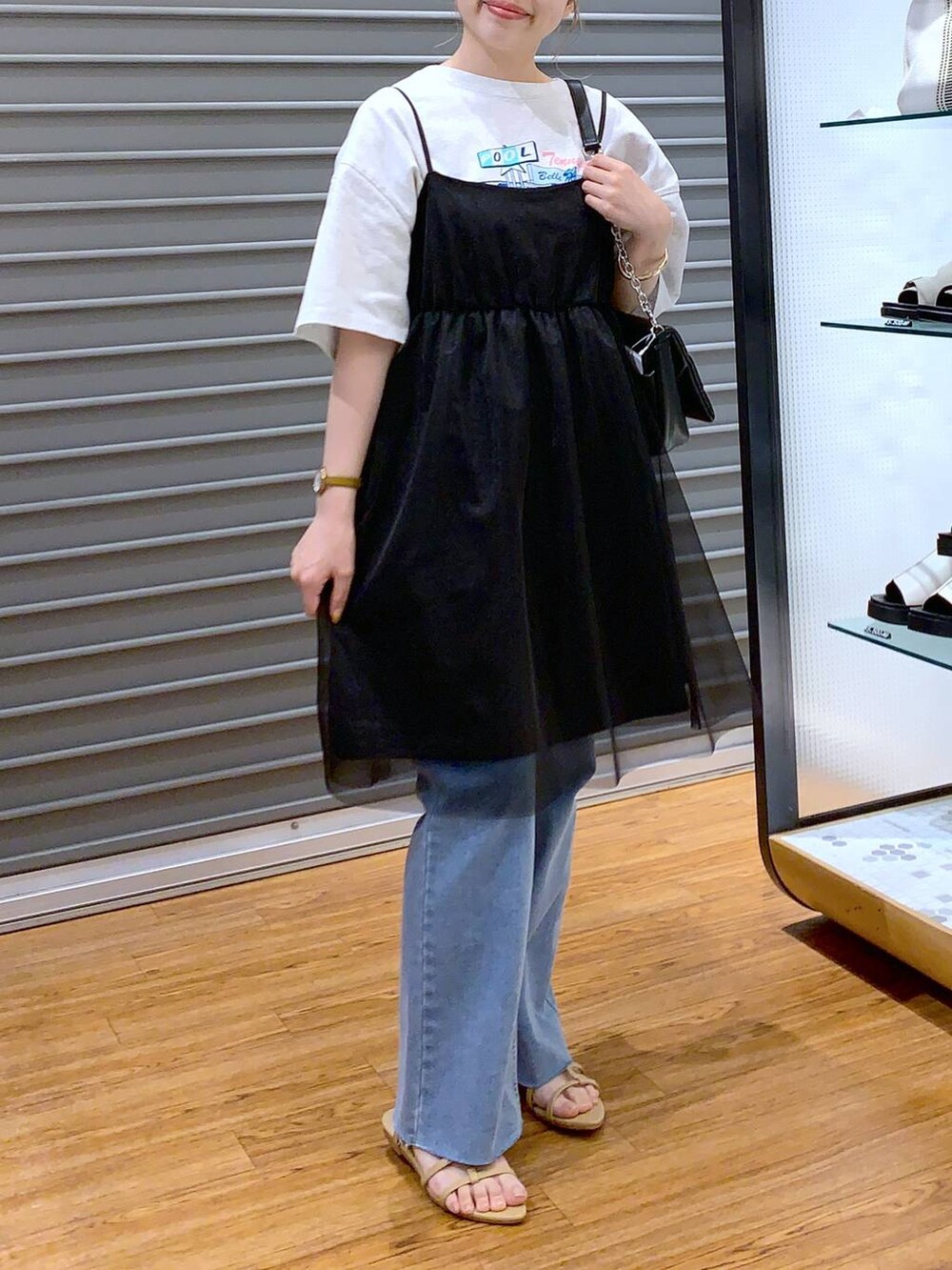 ブラック系のショルダーバッグ、ベージュ系のサンダル、ブルー系のデニムパンツを着用したレディースの夏コーディネートの5枚目の写真