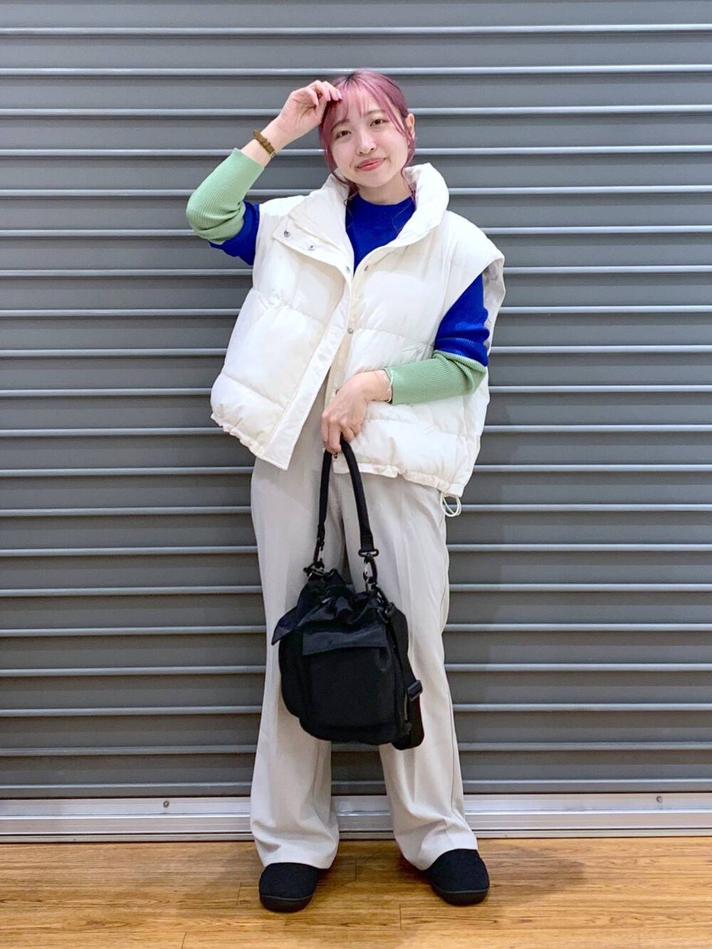 ブラック系のショルダーバッグ、ブルー系のニット/セーター、ホワイト系のダウンベストを着用したレディースの秋コーディネートの5枚目の写真