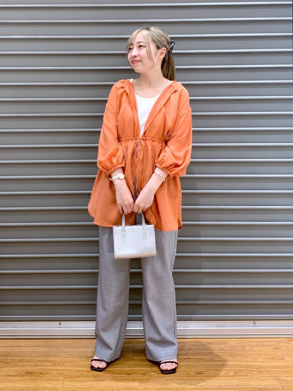 オレンジ系のシャツ/ブラウス、グレー系のショルダーバッグ、ブラック系のサンダルを着用したレディースの夏コーディネートの6枚目の写真