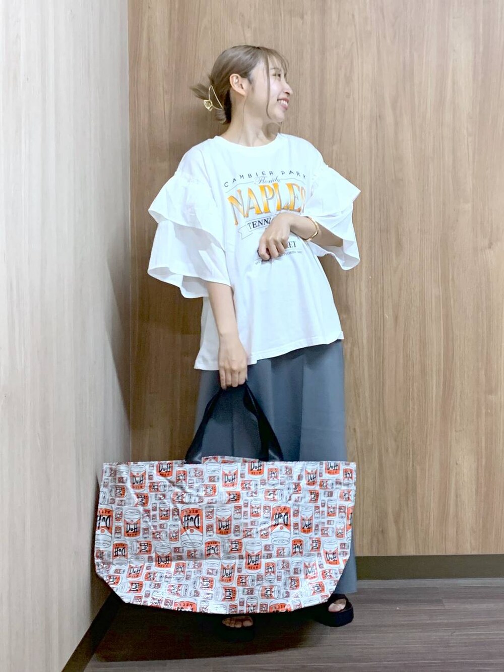 グレー系のスカート、グレー系のトートバッグ、ブラック系のサンダルを着用したレディースの夏コーディネートの2枚目の写真