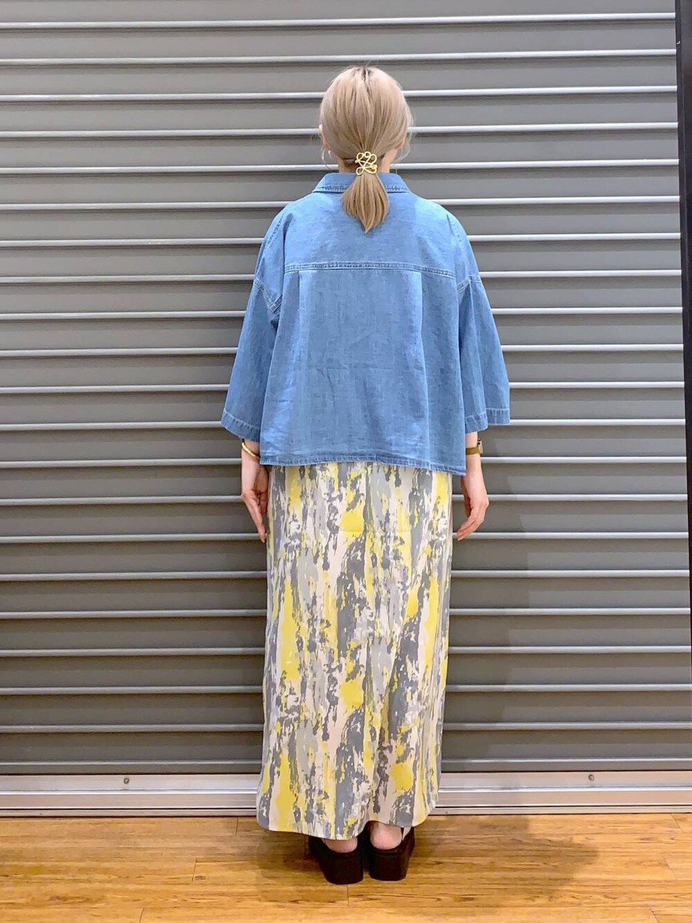 イエロー系のワンピース、ブルー系のシャツ/ブラウス、ホワイト系のサンダルを着用したレディースの夏コーディネートの2枚目の写真